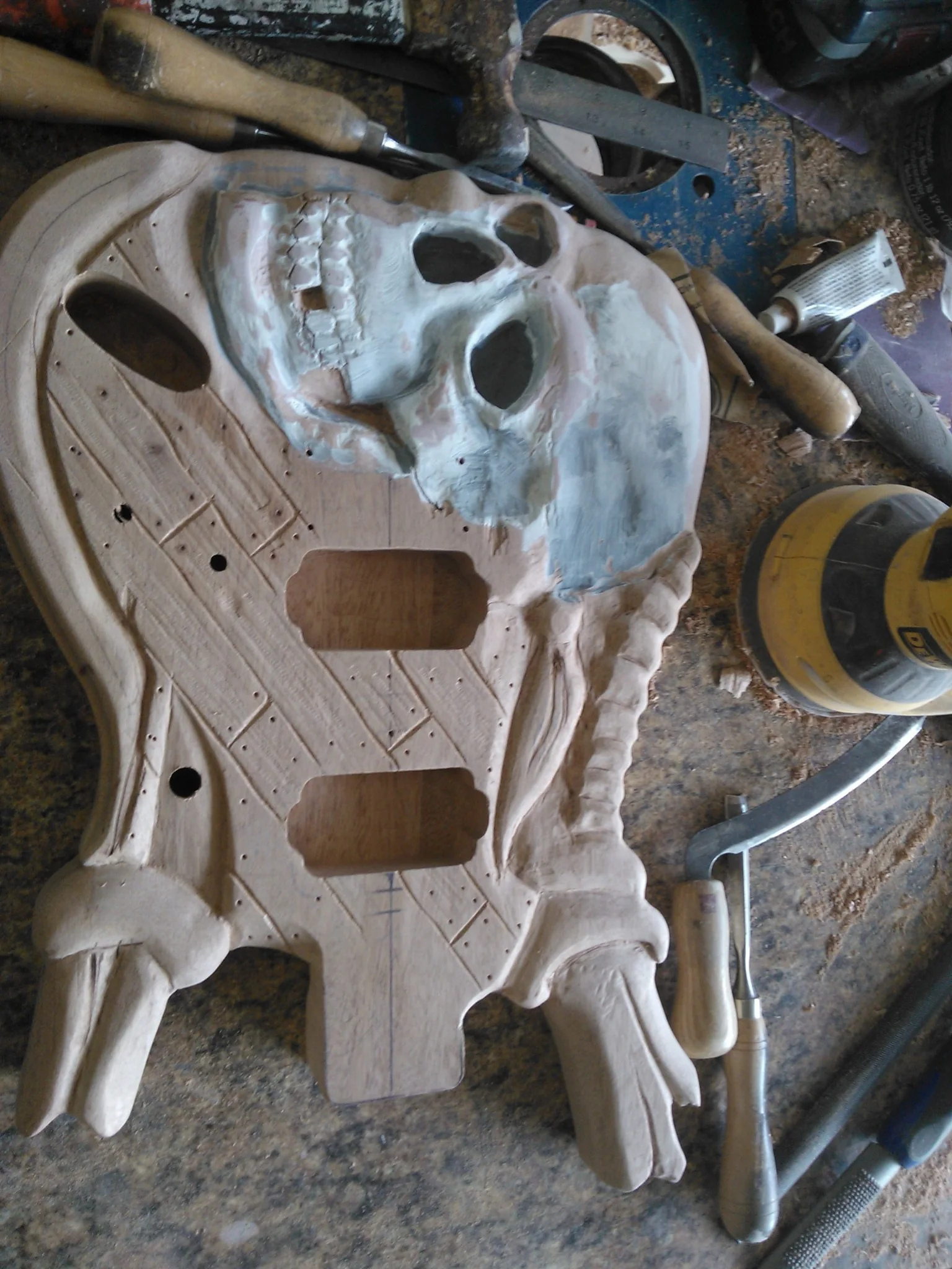 Mahogany pirate guitar body during skull and hand carving