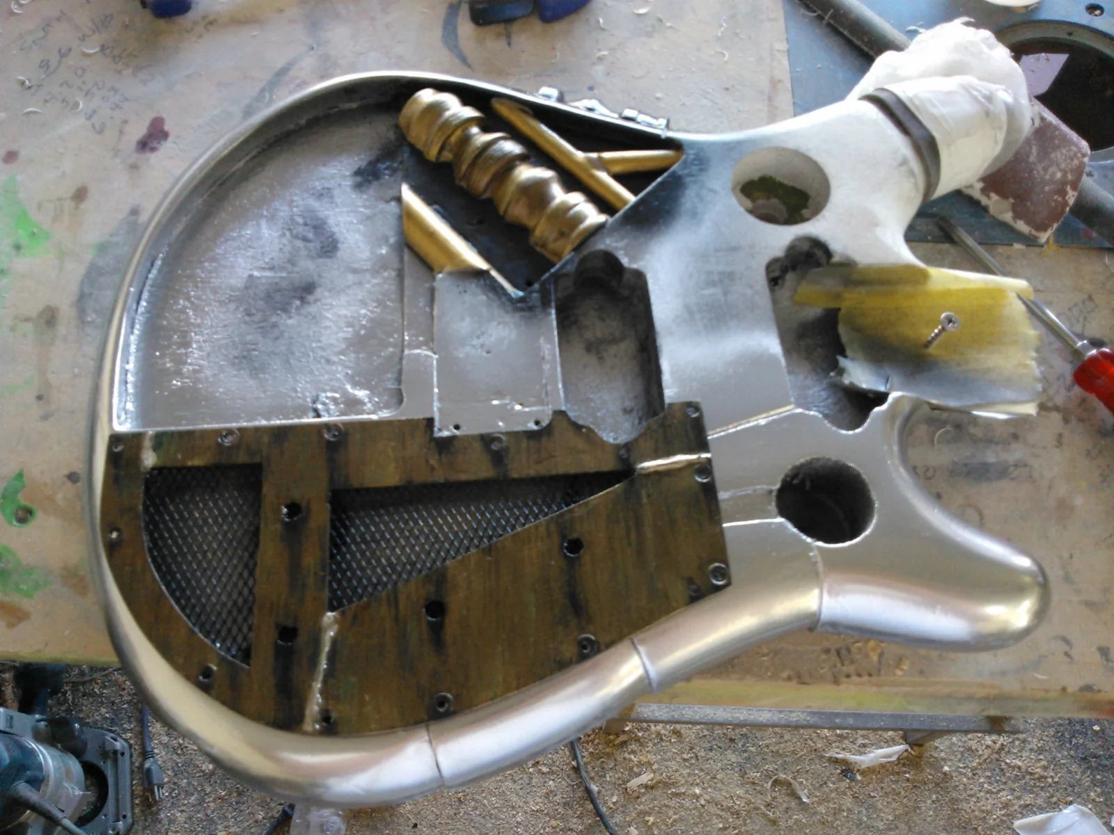 Partially finished steampunk guitar body with aged metal panels and wooden pipes