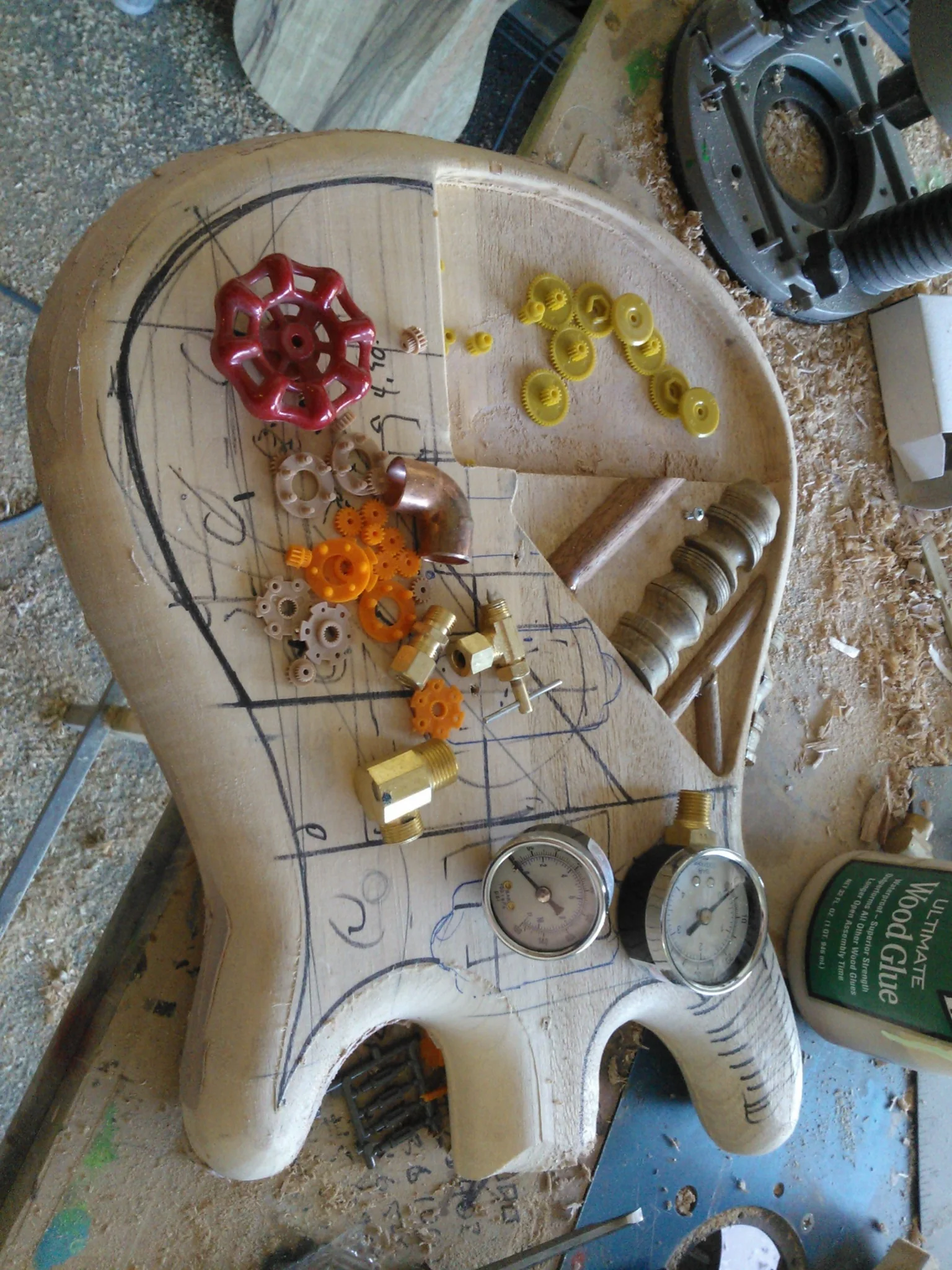 Raw custom guitar body with steampunk components laid out during design